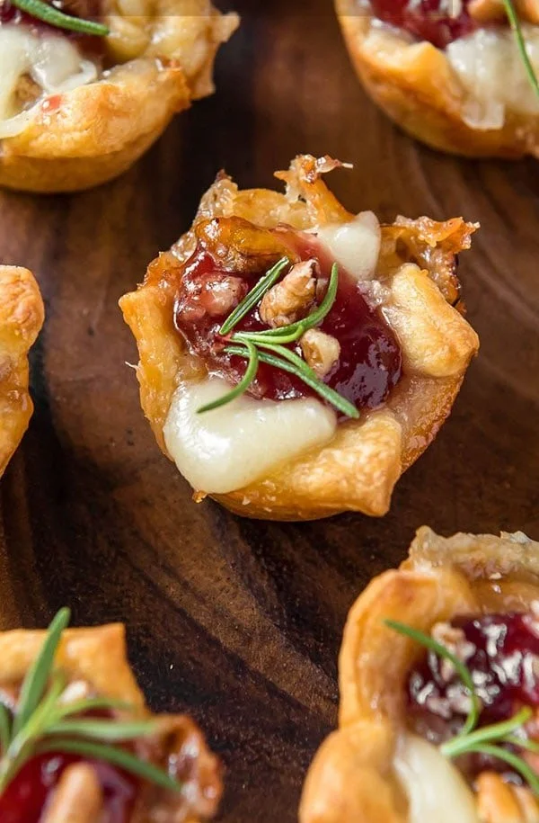Plate of homemade Cranberry Brie Bites topped with fresh herbs