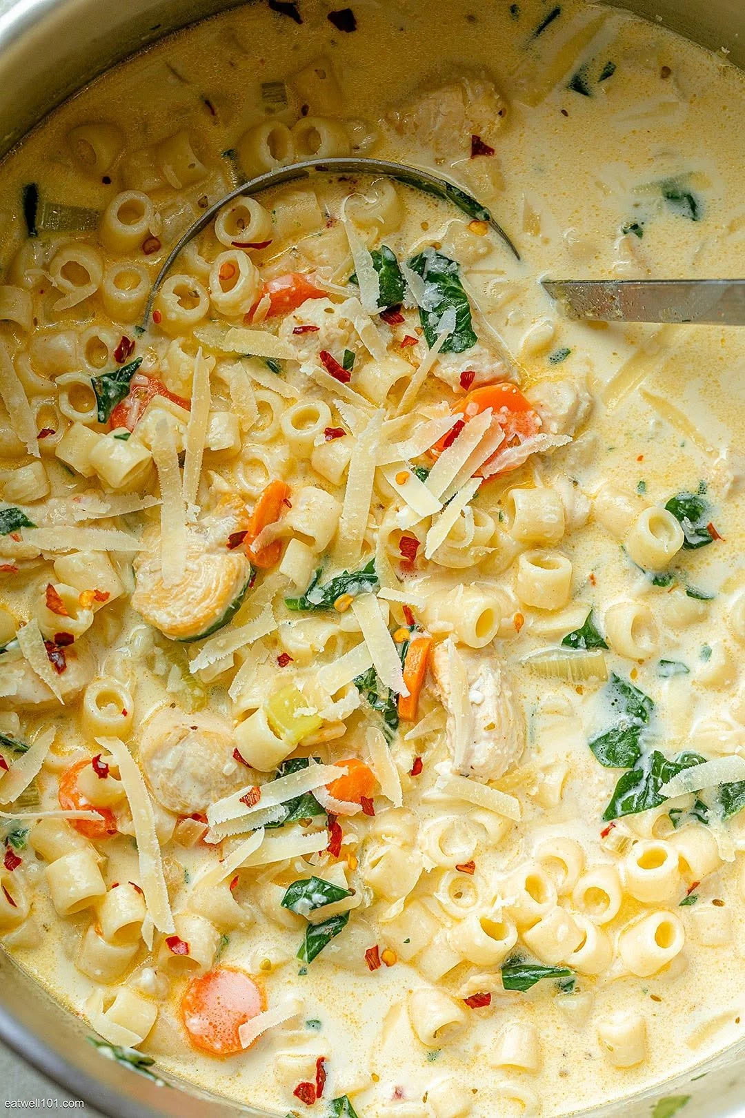 Creamy chicken pasta soup with carrots and spinach in a bowl