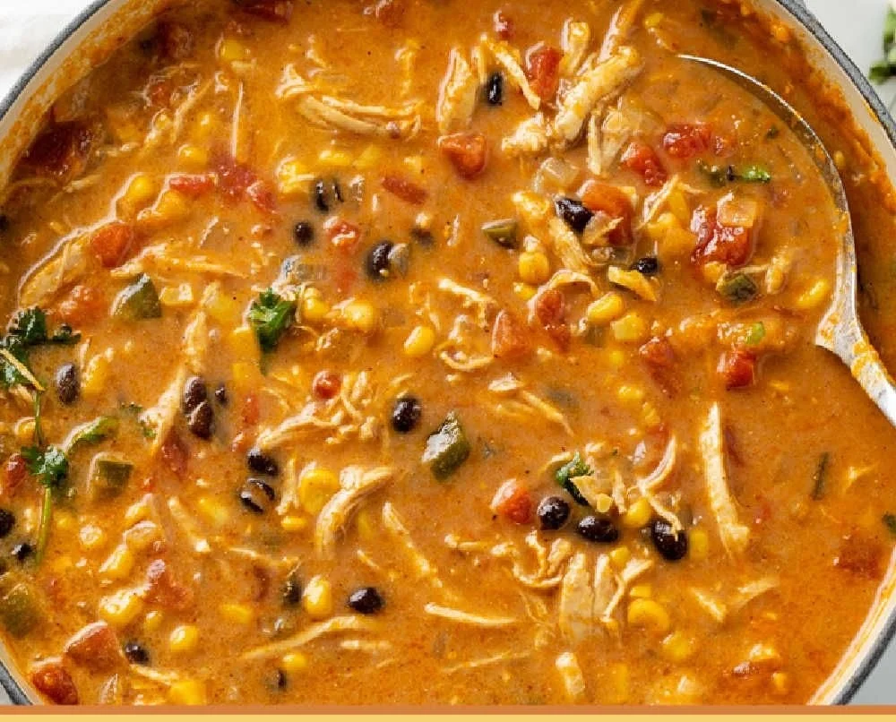 Bowl of creamy chicken tortilla soup topped with avocado and tortilla strips