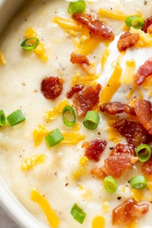 Delicious loaded potato soup topped with cheese, bacon, and chives in a bowl