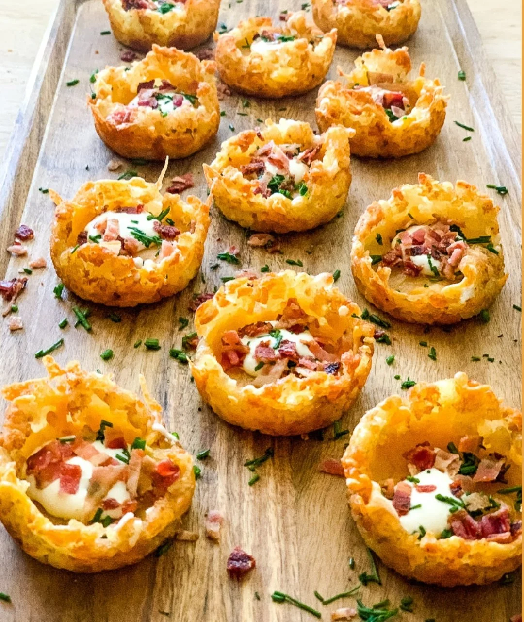 Loaded tater tot appetizers topped with cheese and bacon on a serving platter.