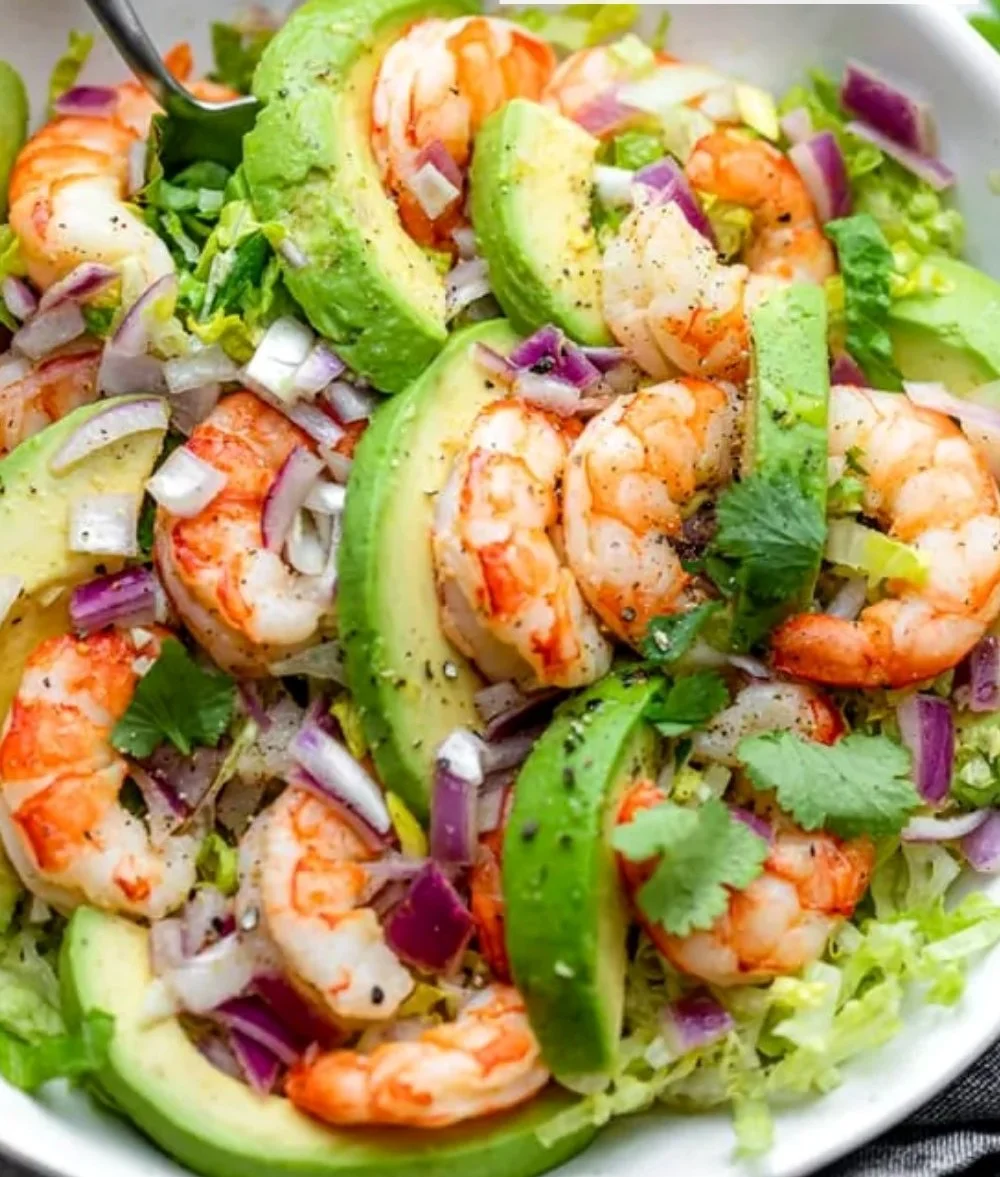 Delicious shrimp and avocado salad served in a bowl, garnished with fresh herbs.