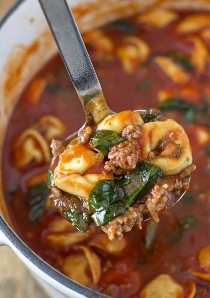 Bowl of Tortellini Soup with Italian Sausage and Spinach topped with herbs
