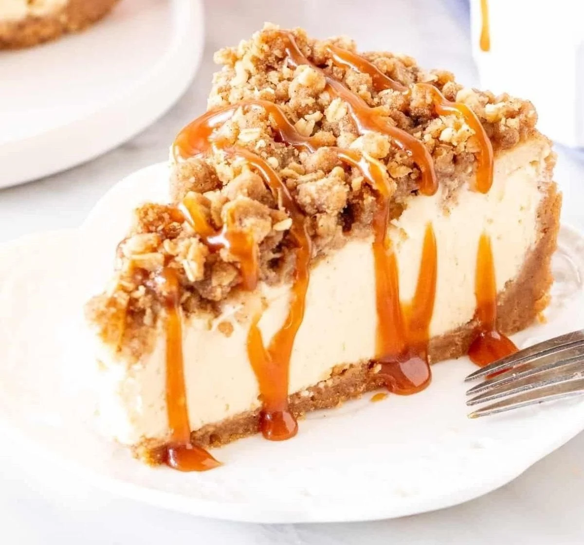 A slice of apple crisp cheesecake topped with caramel and cinnamon apples