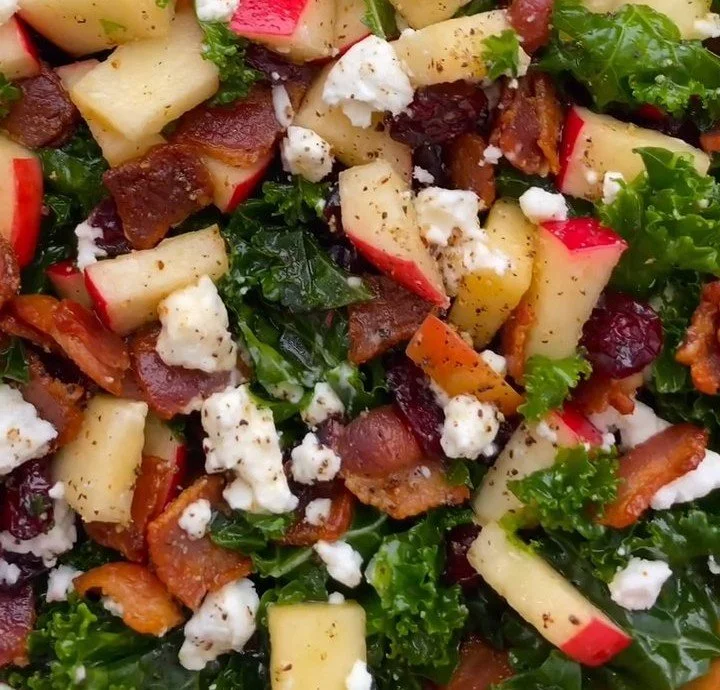 Apple Kale Salad with cranberries and bacon on a plate, garnished with nuts.