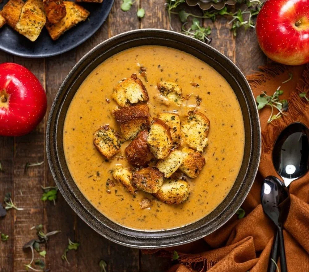 Bowl of creamy roasted apple and pumpkin soup garnished with herbs