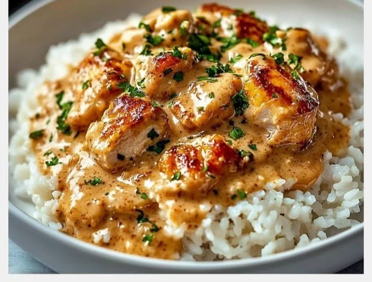 Creamy smothered chicken served over rice in a skillet