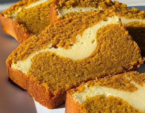 A slice of easy pumpkin cheesecake bread on a plate with autumn decorations.