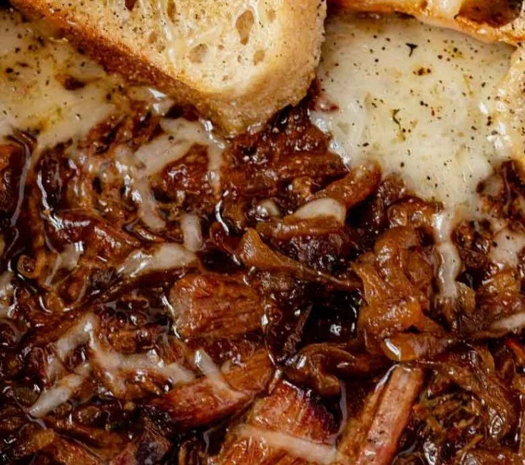 Delicious French onion pot roast served with melted cheese and herbs