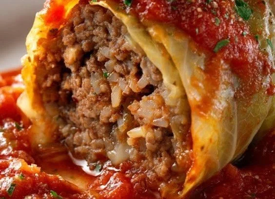 Delicious homemade stuffed cabbage rolls on a plate garnished with herbs.