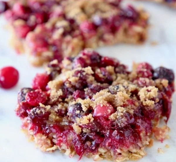 Delicious homemade oatmeal cranberry bars cut into squares on a wooden table.