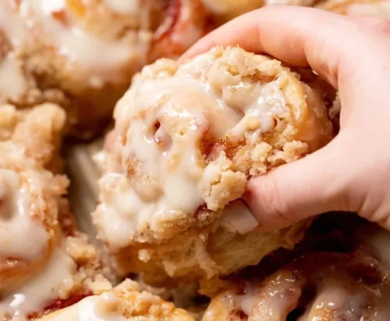 Delicious peach cobbler cinnamon rolls with crumb streusel topping on a plate