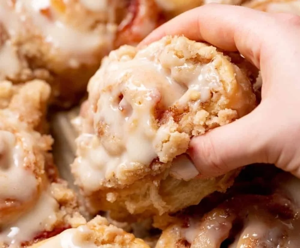 Delicious peach cobbler cinnamon rolls with crumb streusel topping on a plate