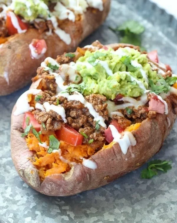 Taco-stuffed sweet potatoes topped with fresh ingredients in a bowl