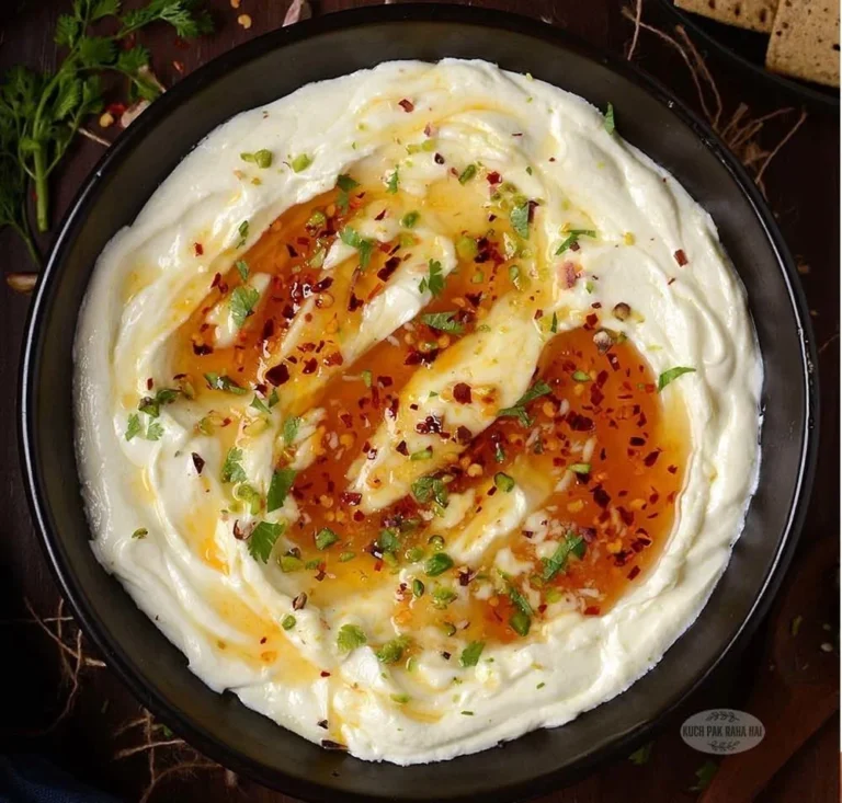 Whipped feta dip with honey served in a bowl with fresh herbs and bread