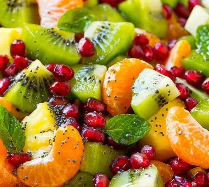 Bowl of winter fruit salad featuring citrus fruits, pomegranates, and berries.